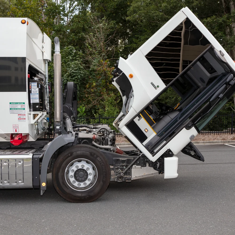 Freightliner refuse collection truck with worker picking up garbage bin in suburb